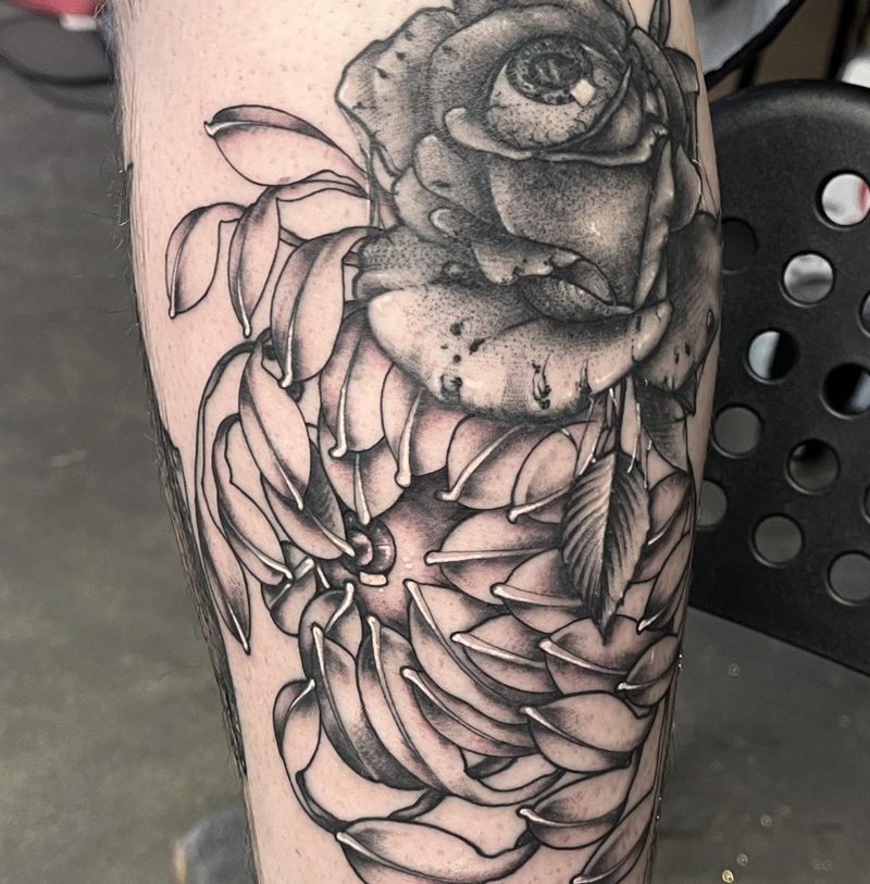 Black and grey rose and chrysanthemum tattoo on a calf