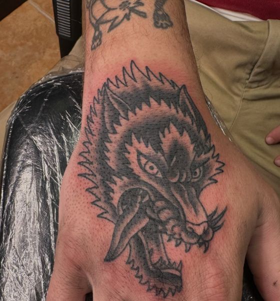 Black and grey wolf head tattoo on a hand