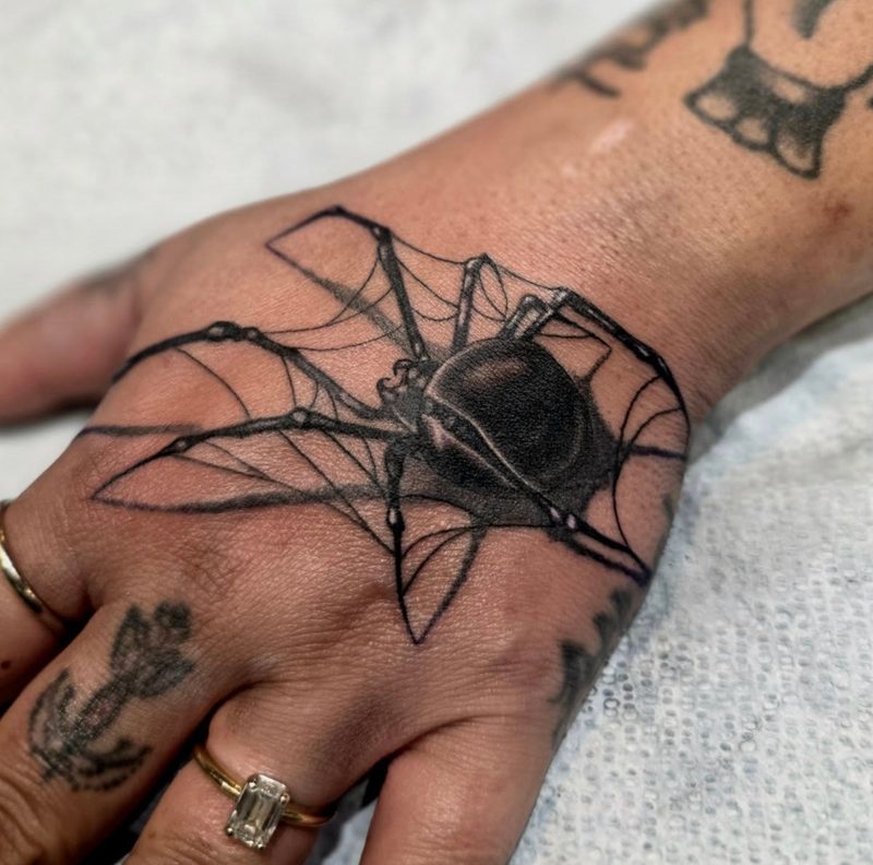 Black widow spider and web tattoo on a hand